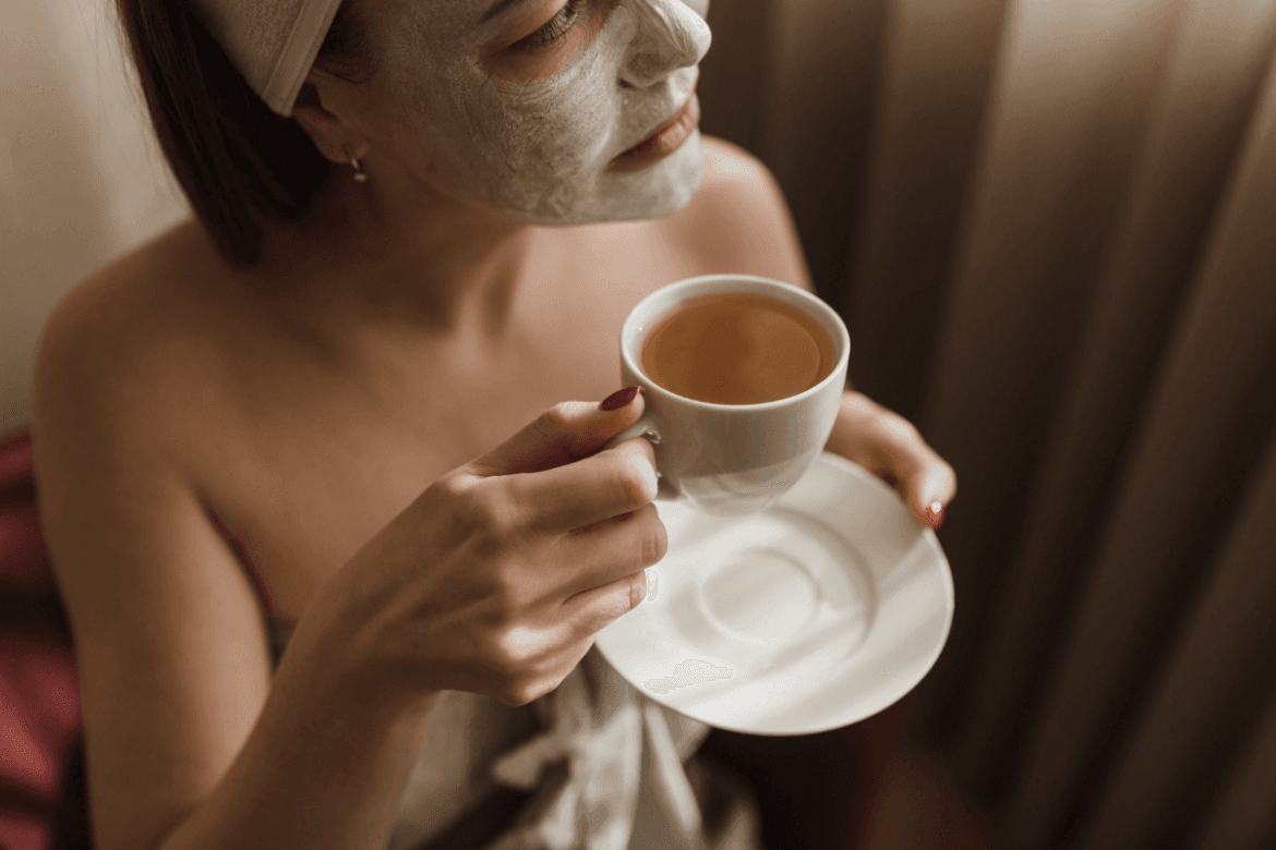 a person with a mask on their face holding a cup of tea