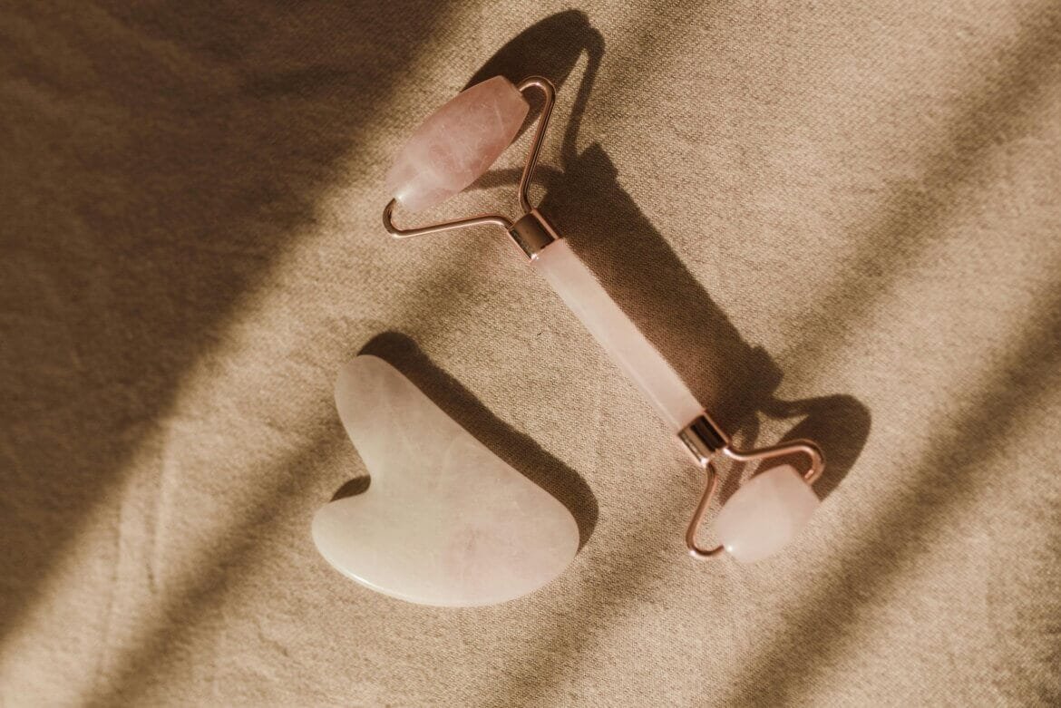 jade roller and a gua sha stone placed on a soft surface, likely used for skincare