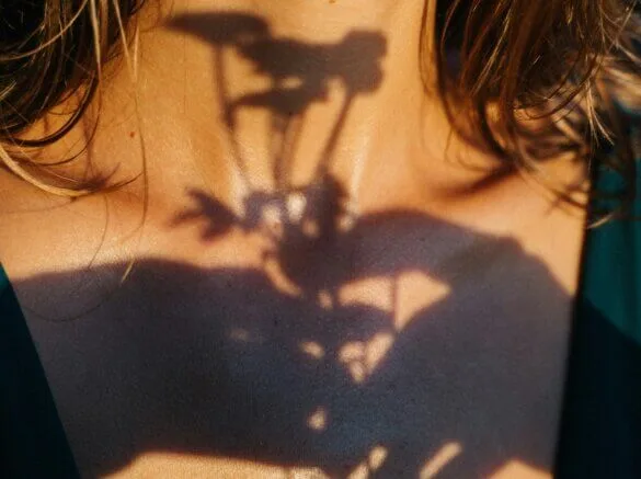 Shadow of a plant on neck, light creating artistic contrast.
