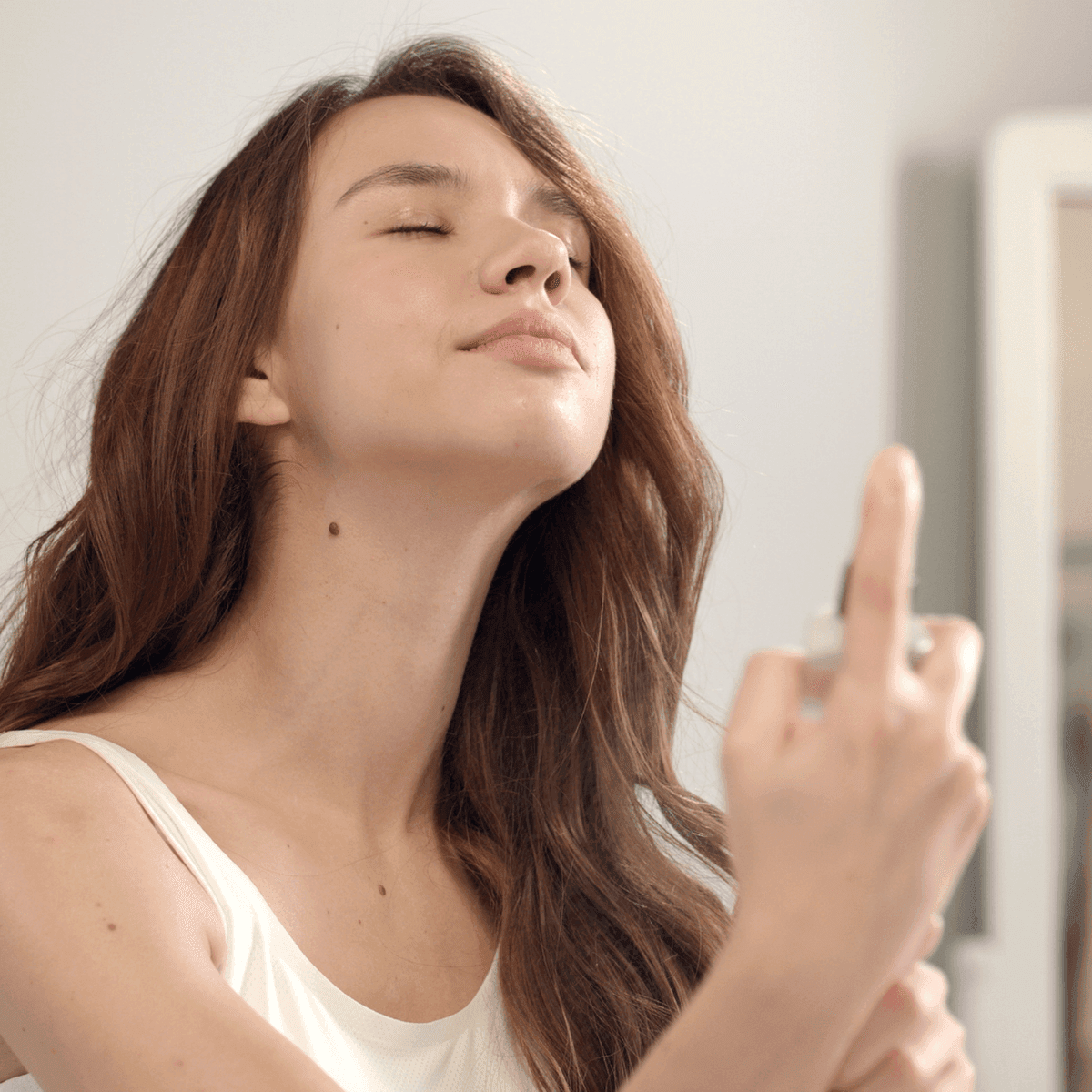 woman applying setting spray to her face