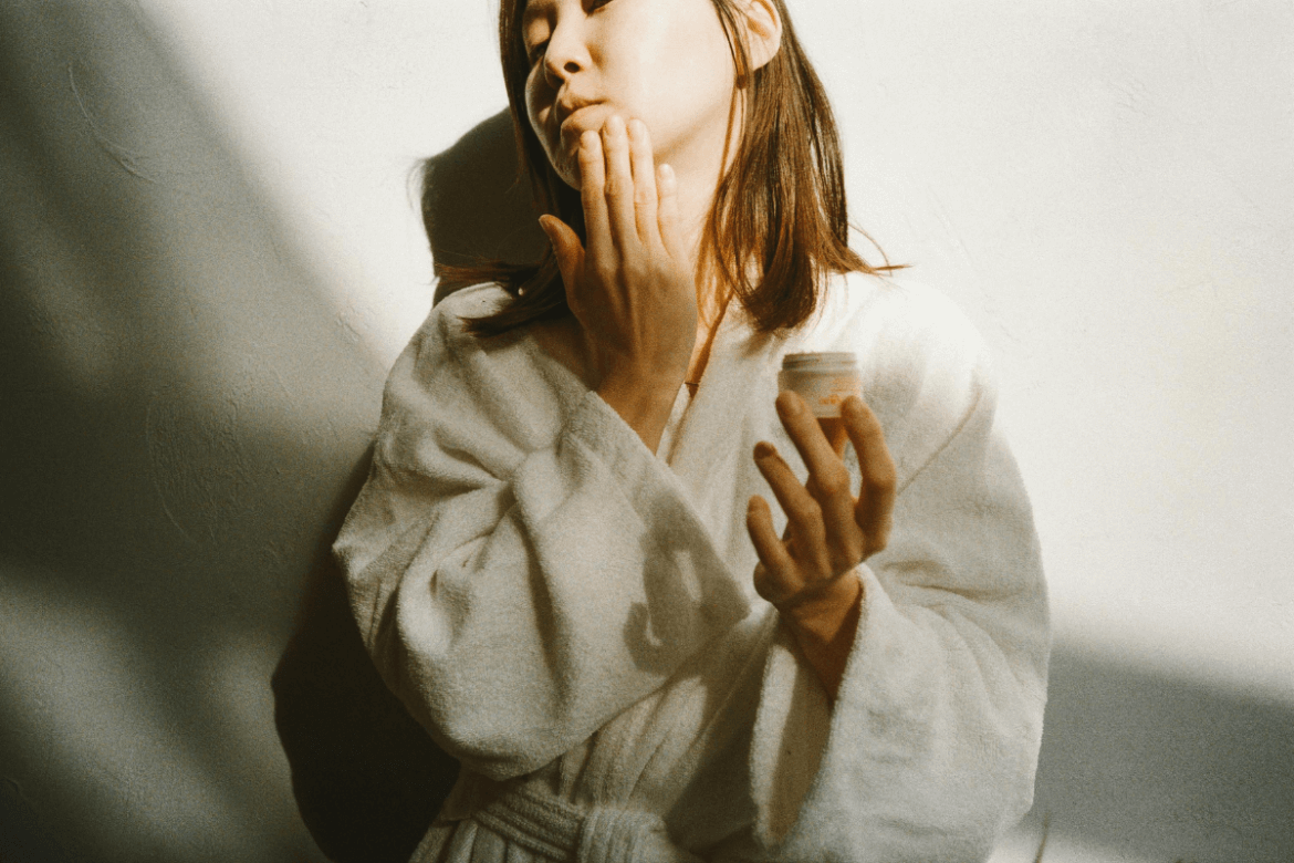 girl holding cream and applying it on her face