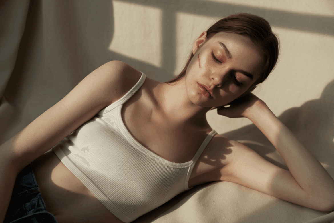 A young woman with a scar resting in soft light.