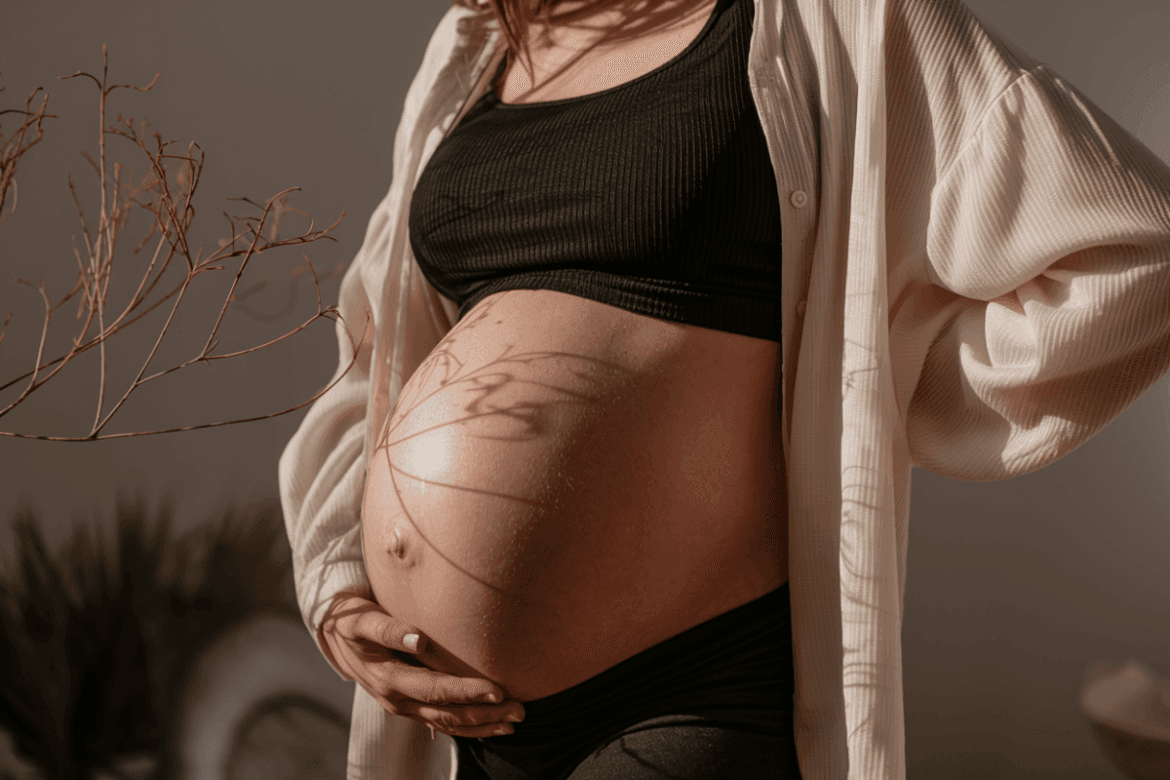 a pregnant woman wearing a black crop top holding her belly